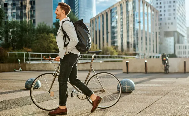 mies taluttaa pyörää kaupunkiympäristössä
